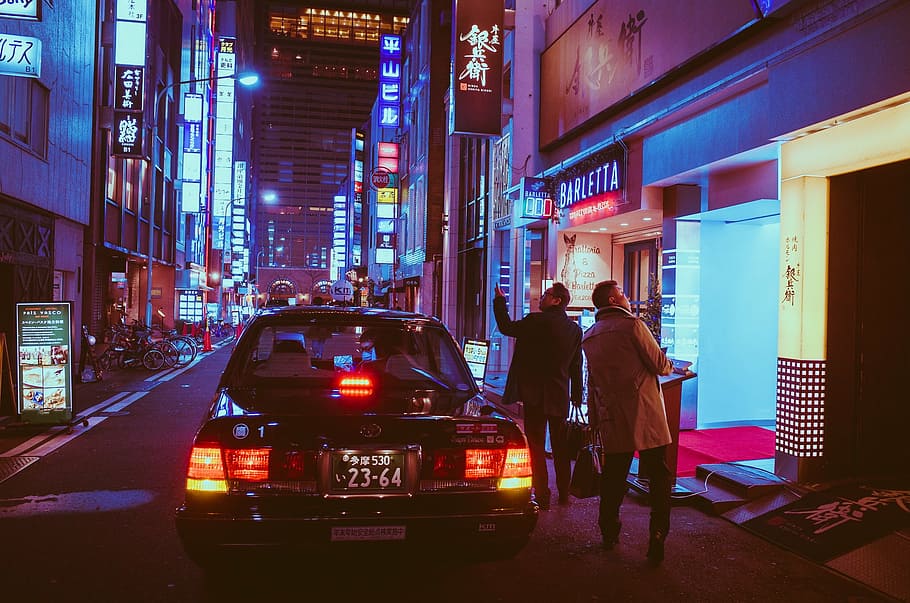 two man beside car staring up on building during nighttime, japan