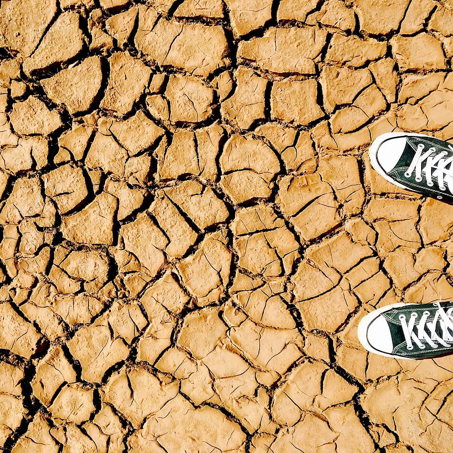 pair of lace-up sneakers on cracked ground, clay, cracks, dry HD wallpaper