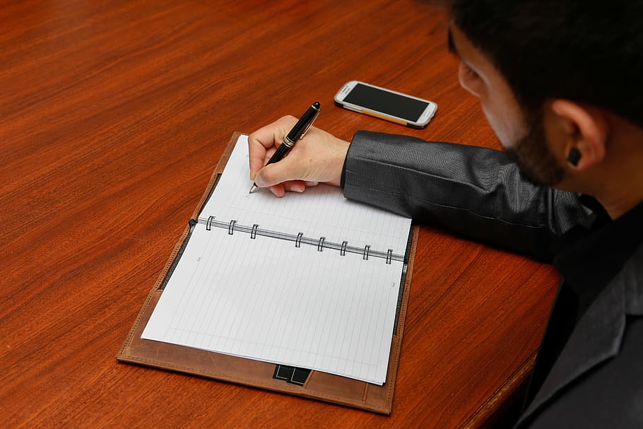 person writing on white planner, organizer, brown leather, executive HD wallpaper