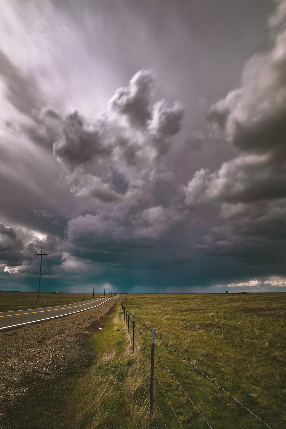 scenery of plain field, gray asphalt road surrounded by green grass under gray cloudy sky during daytime HD wallpaper
