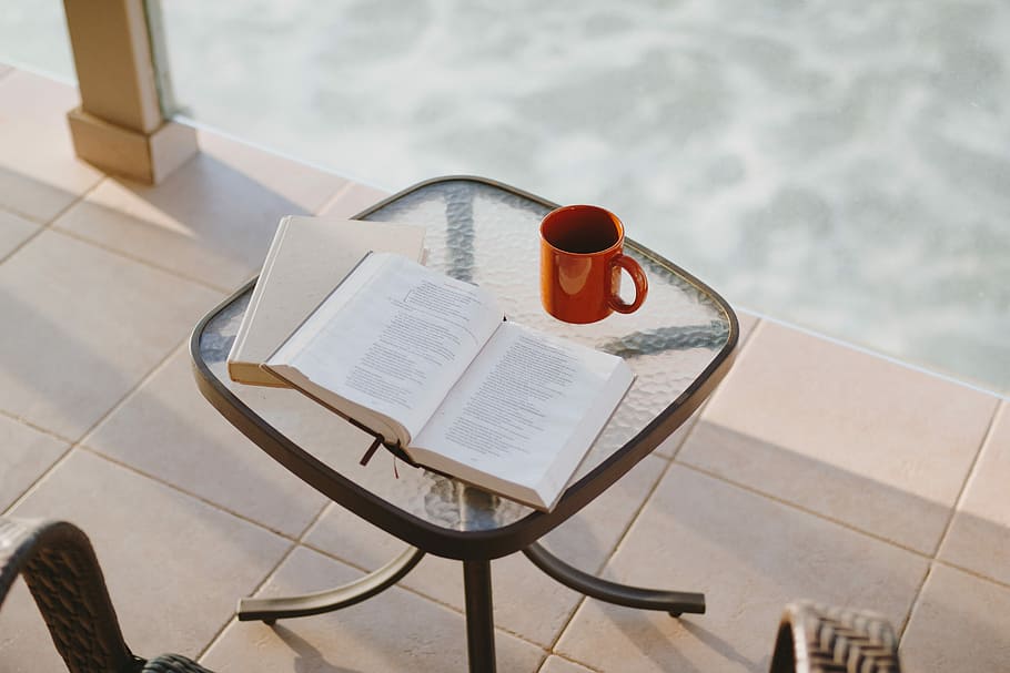 book beside mug on square clear glass-top table, opened book near red ceramic mug above clear glass table HD wallpaper