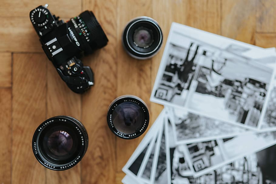 Old Zenit camera and a Canon camera with black-and-white photos on a wooden table HD wallpaper