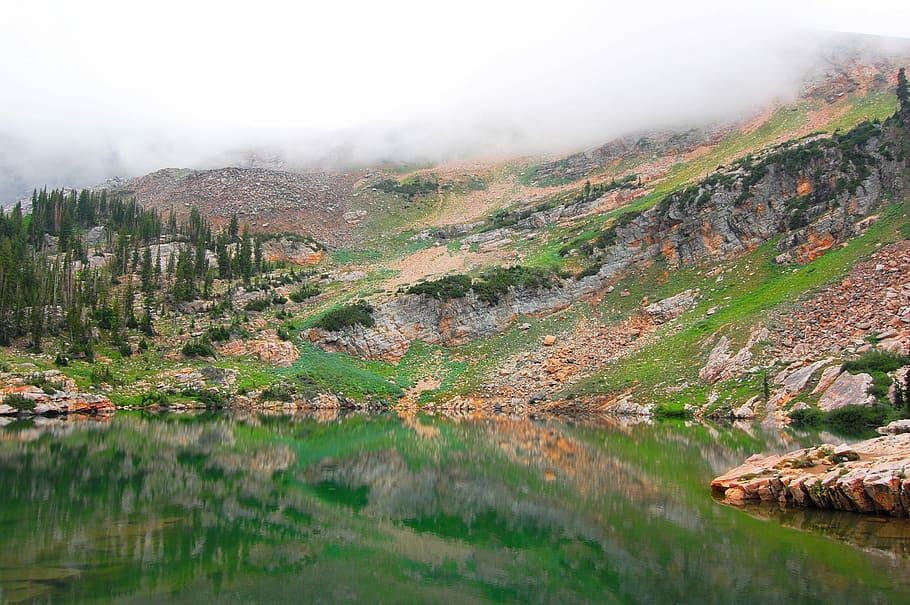 fog on top of mountain, landscape photography of body of water beside mountain covered by fog HD wallpaper