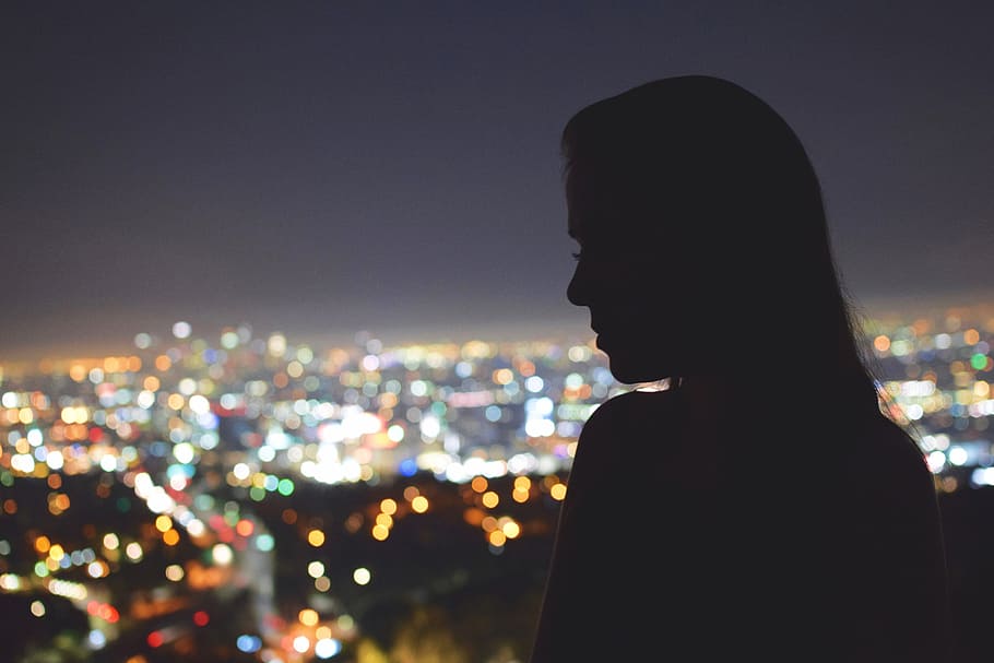 Silhouette of a woman looking over the city of Los Angeles at night