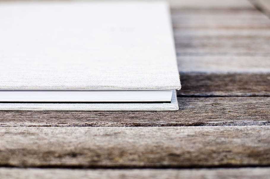 White hardcover book sitting on the wooden table, white book HD wallpaper