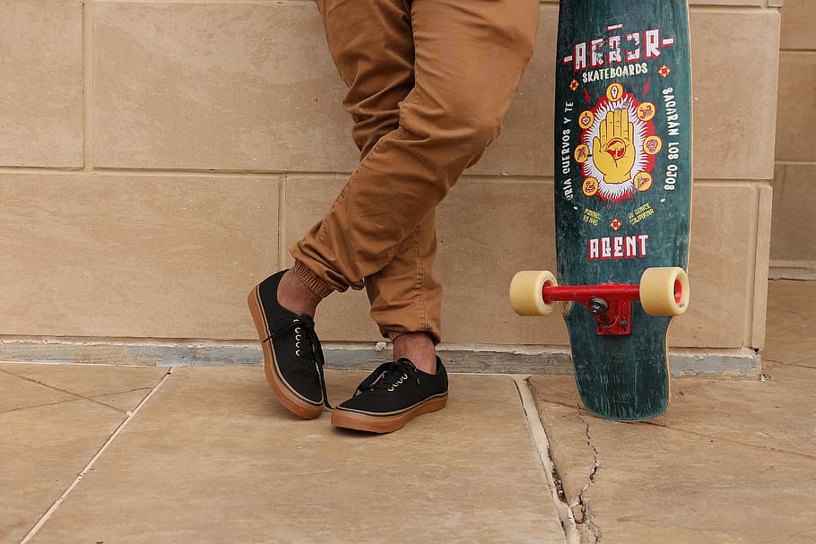 man holding longboard leaning on wall, person, wearing, brown HD wallpaper