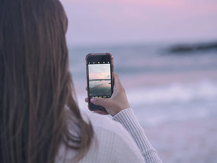 woman capturing image using her smartphone, selective focus photography of woman holding space gray iPhone using camera and capturing photos HD wallpaper