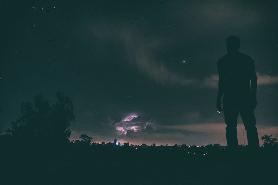 silhouette of man standing under night sky, man standing on ground looking at sky during nighttime
