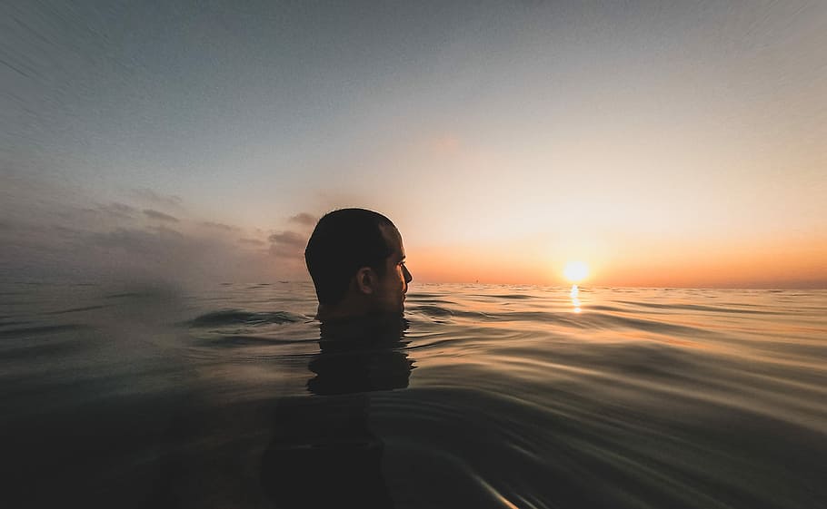 man on body of water, sunset, orange, yellow, blue, black, ripple HD wallpaper