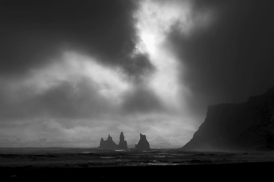 grayscale photo of rock formation surrounded by water, silhouette of mountains surrounded by body of water HD wallpaper