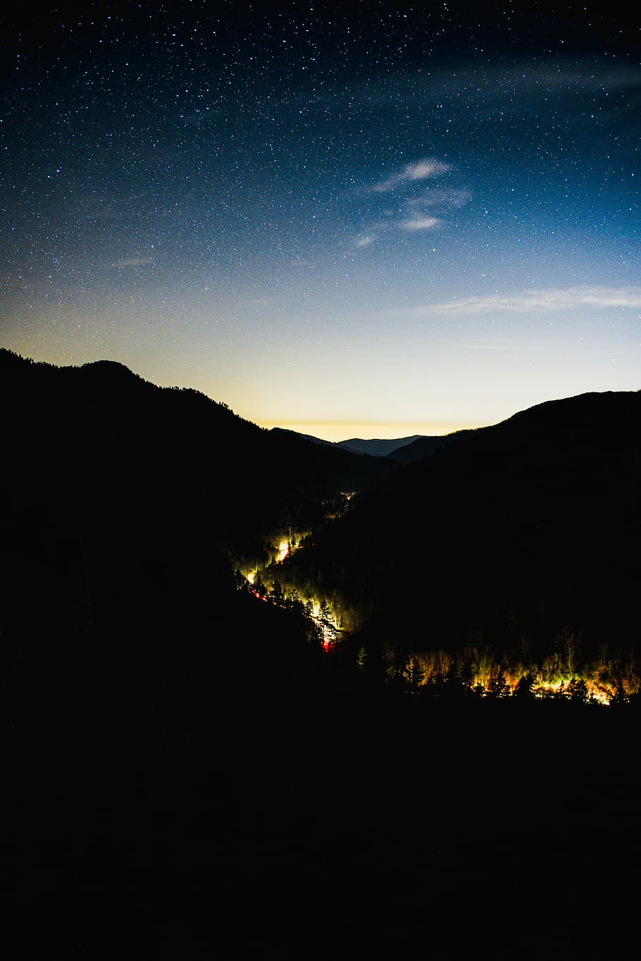 house lights between hills, lighted road in the middle of mountain silhouette under blue sky at night HD wallpaper