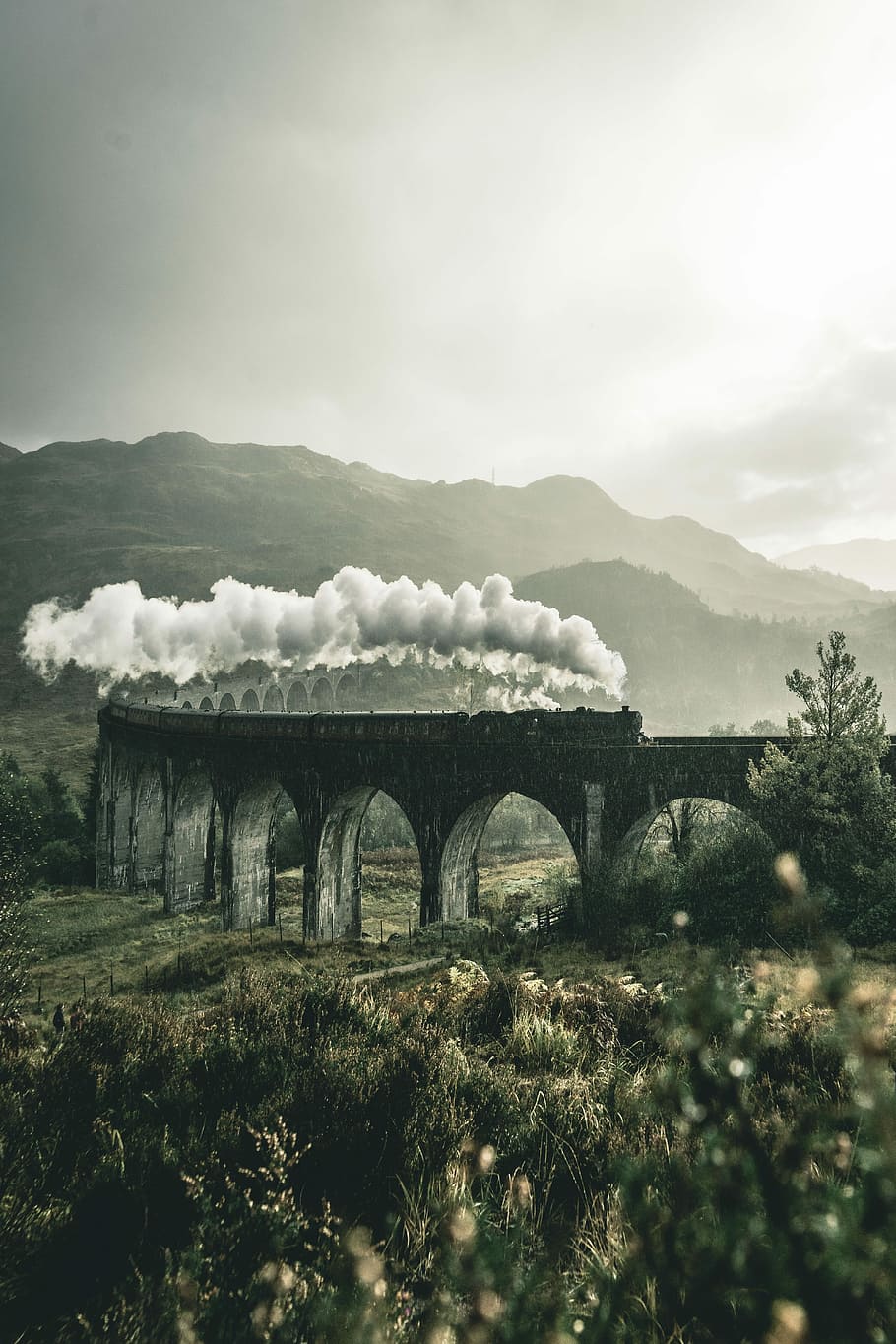 black train on railway bridge under heavy clouds, train running during daytime HD wallpaper