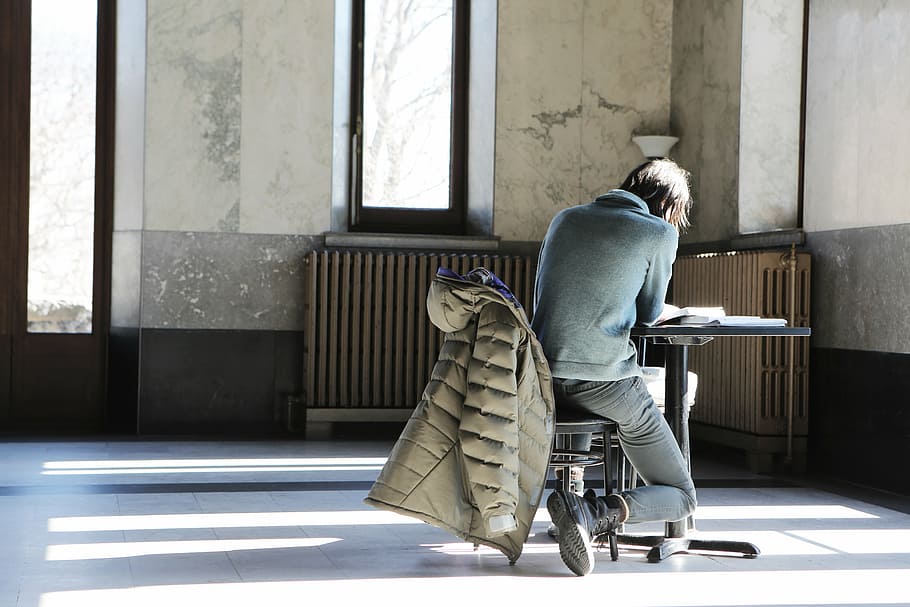 books, chair, man, person, reading, room, sitting, solo, table