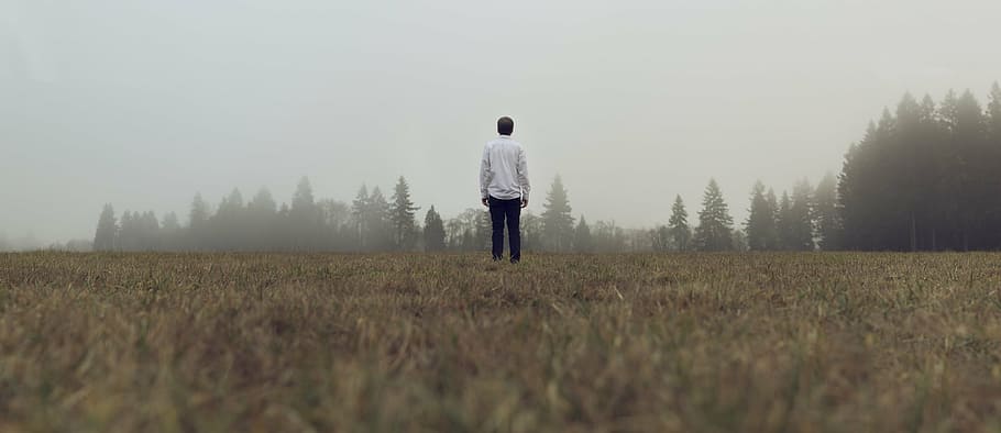 man in white dress shirt standing on brown grass field at daytime HD wallpaper