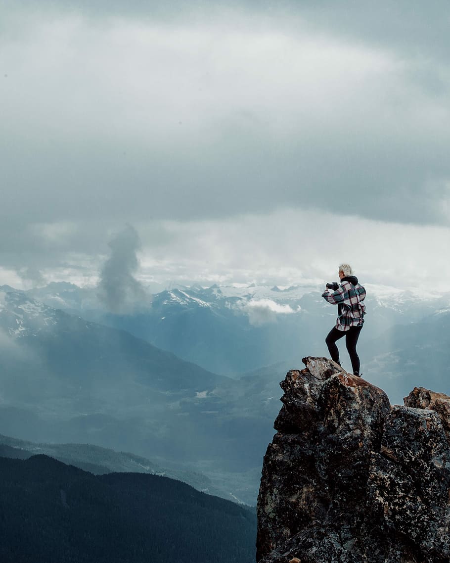 person standing on top of rock mountain during daytime, person on top of the mountain overlooking the mountains HD wallpaper