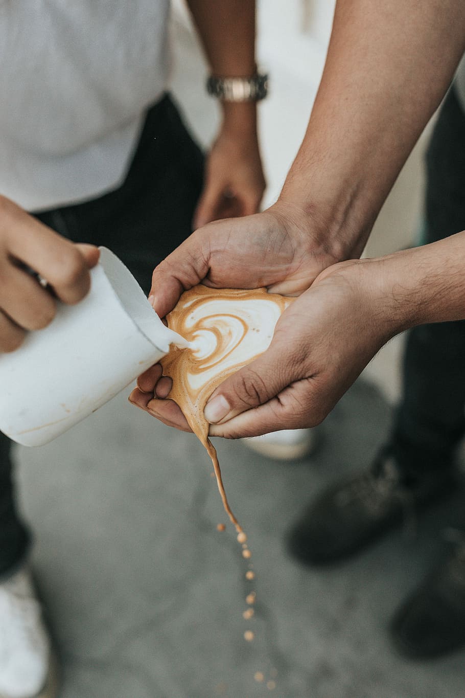 white and brown liquid poured on person's palms, person pouring coffee latte on person's hands selective focus photography HD wallpaper