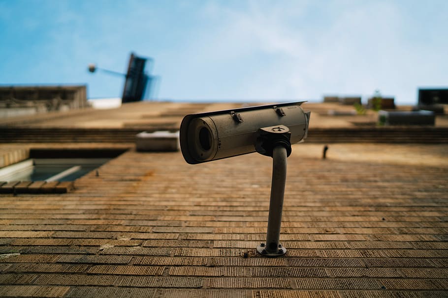 shallow focus photography of gray security camera, white surveillance camera mounted on brown concrete brick wall