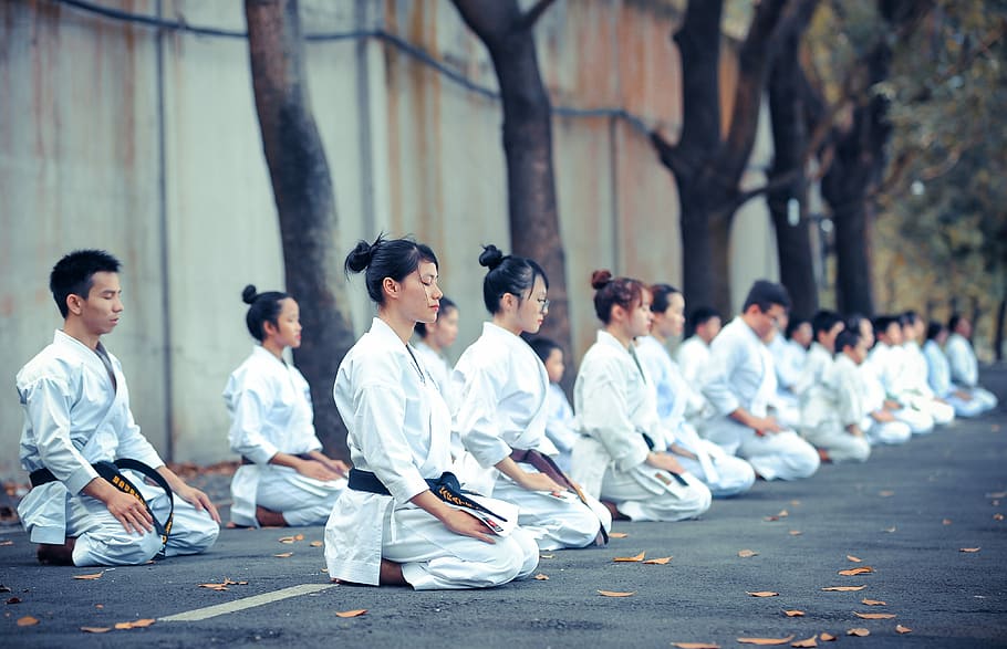 group of martial artists sitting on the grounds, group of people meditating on floor