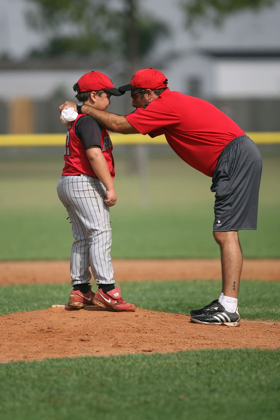 selective focus photo of man talking boy in baseball field during daytime