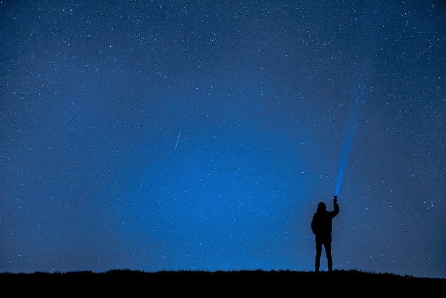 person silhouette holding flashlight on blue sky, night photograph, HD wallpaper