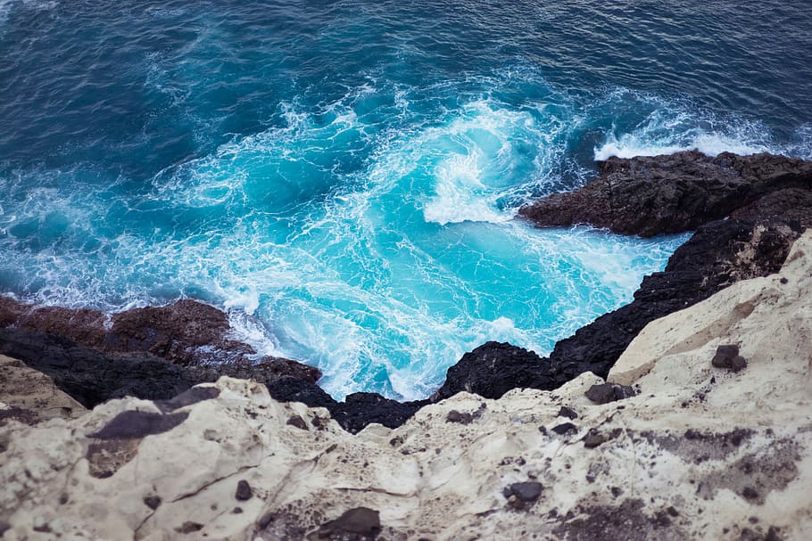 top view photo of ocean waves unto mountain shoreline, body of water near rock formation, HD wallpaper
