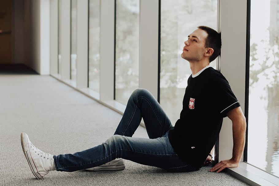 man sitting and leaning on white pillar beside window panel, man sitting on floor while leaning on wall HD wallpaper