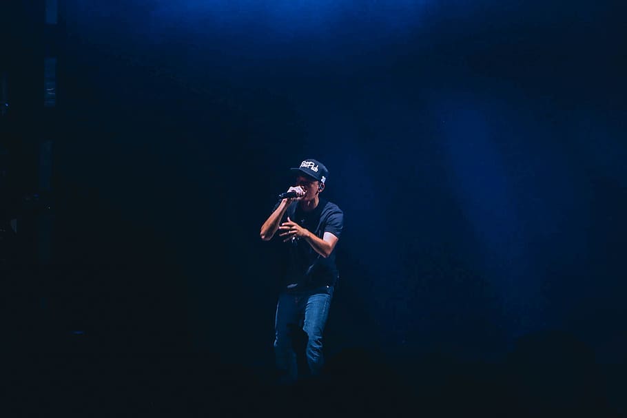man singing inside dim room, man wearing cap singing white using microphne HD wallpaper