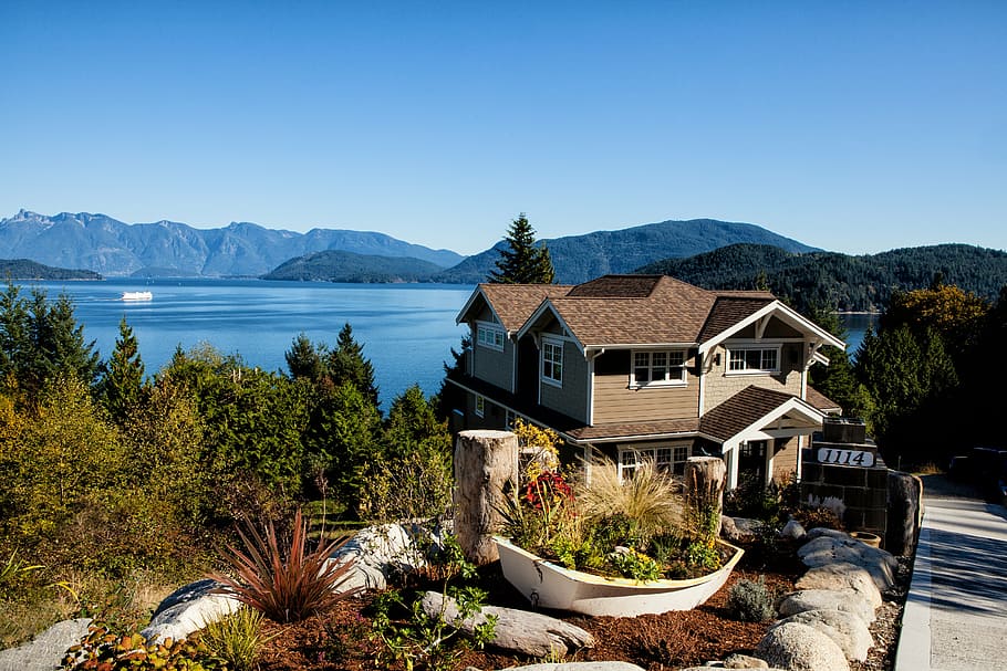 aerial photography of brown 2-story house near trees and blue calm body of water during daytime HD wallpaper