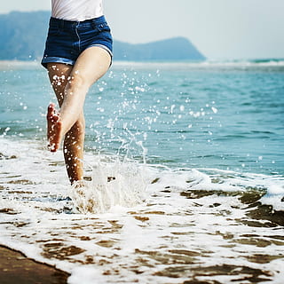 woman in white top and denim shorts on body of water, bare HD wallpaper