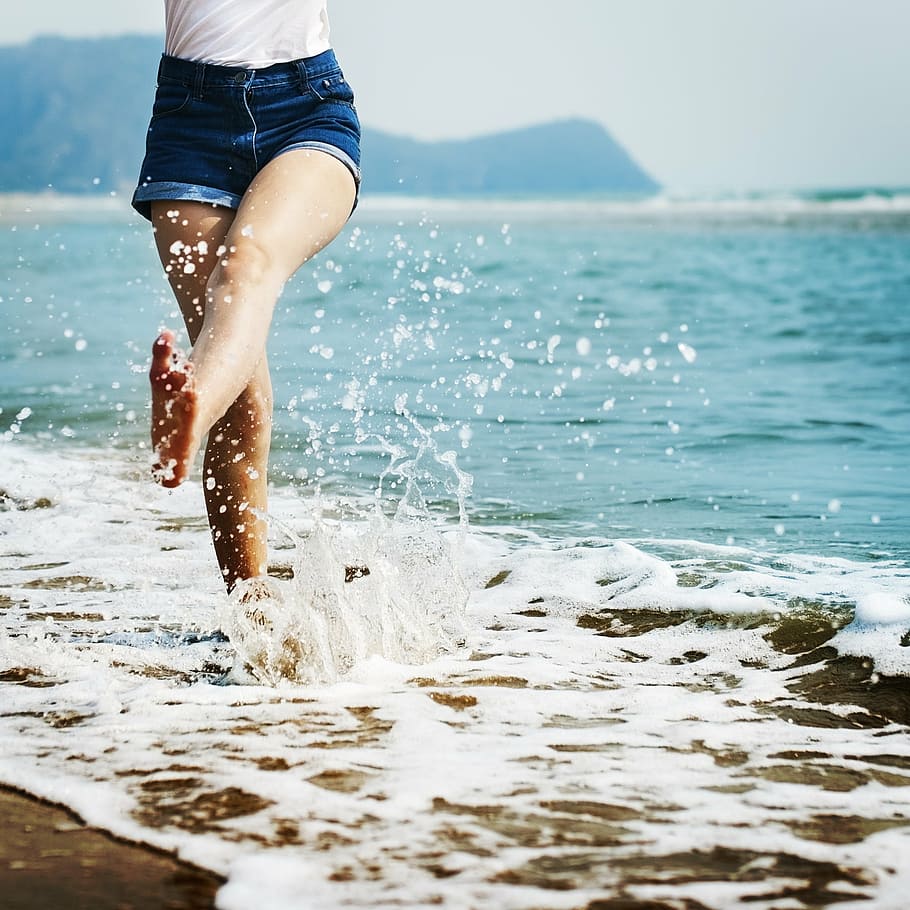 woman in white top and denim shorts on body of water, bare HD wallpaper