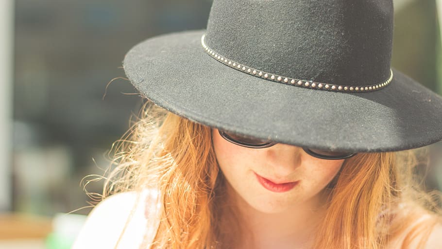 woman looking down wearing black bowler hat, woman wearing black sunglasses and black hat