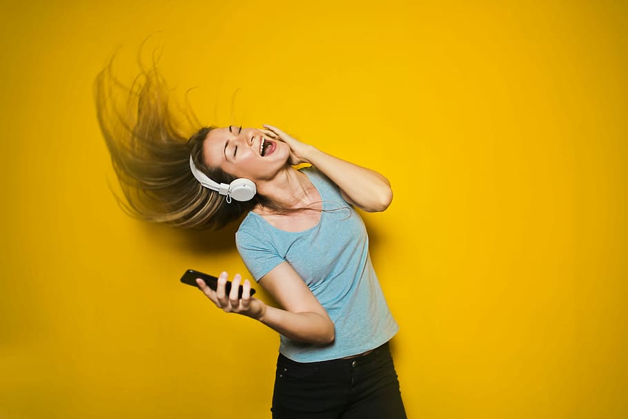 woman wearing white headphones, woman listening to music while holding smartphone HD wallpaper