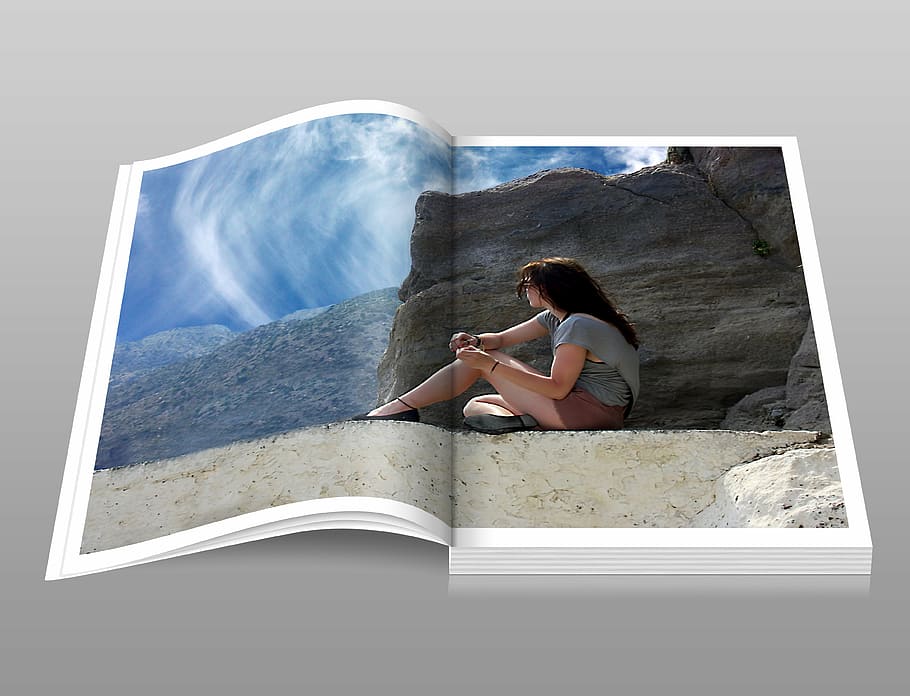 photo of open book page displaying woman sitting near brown rock during day time HD wallpaper