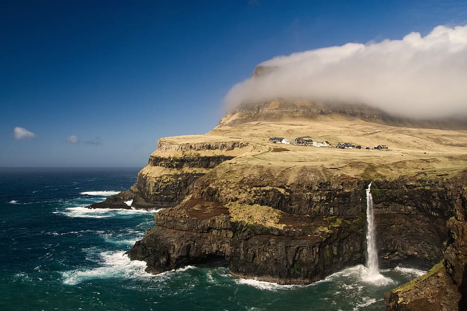 photo of mountain near body of water, water splashing on brown cliff HD wallpaper