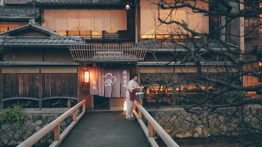 Japanese wooden house with woman in white clothes near river and bridge HD wallpaper