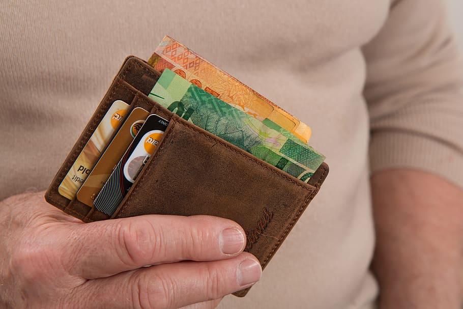 person holding wallet with banknotes and cards in it, credit card