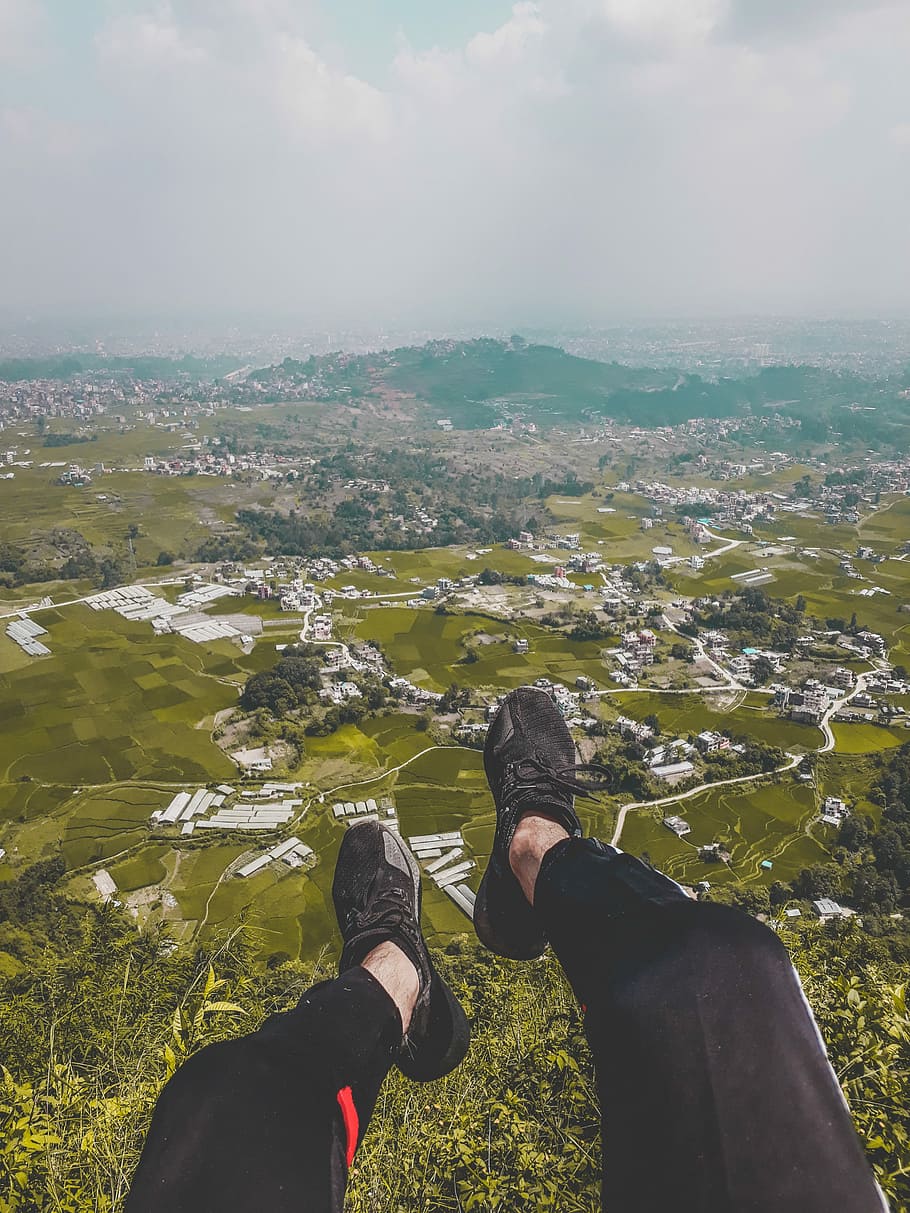 aerial photography of town and mountain, person on hill near village HD wallpaper