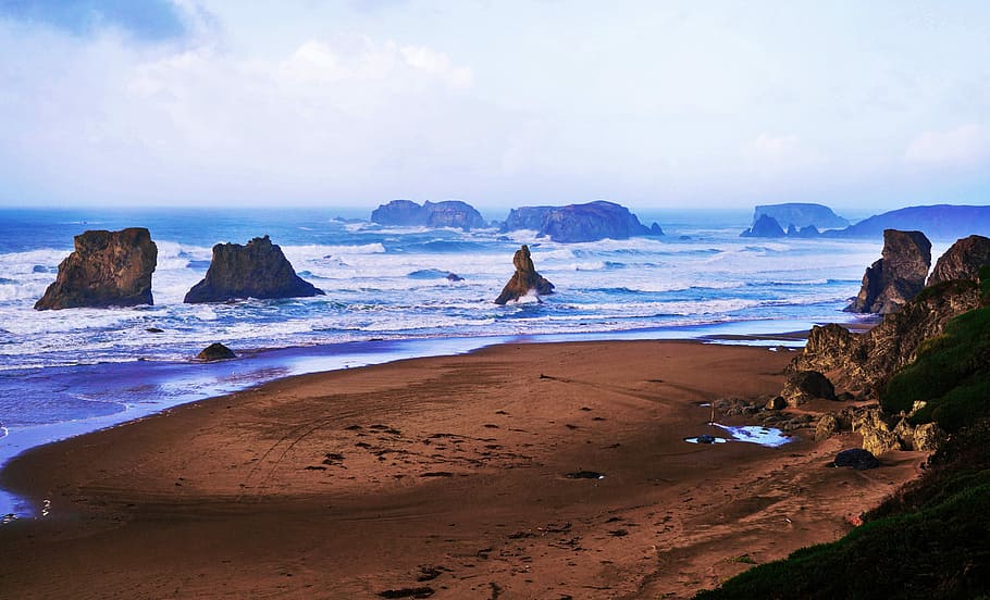 sea waves splashing on rocks, brown sand with body water during daytime HD wallpaper