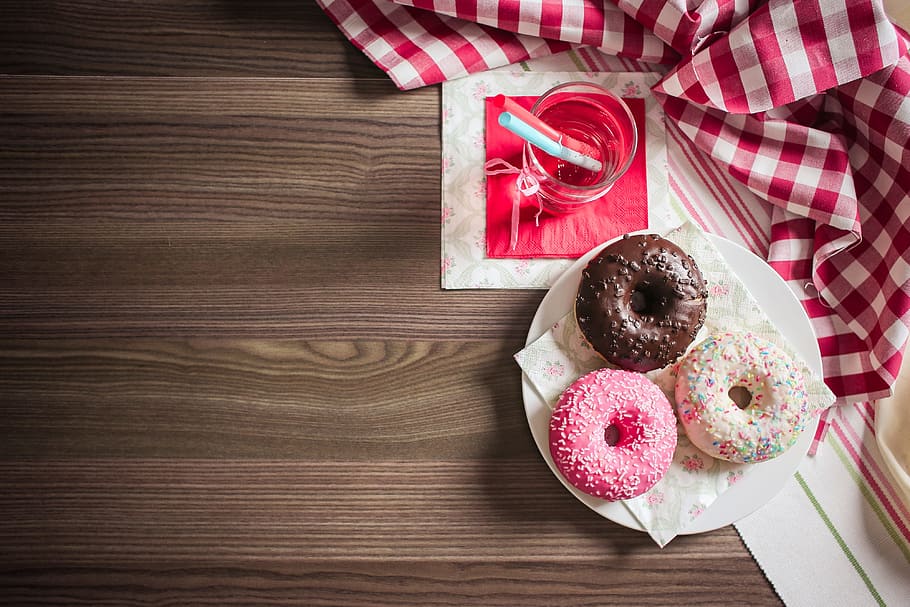 three doughnut place on white ceramic plate beside clear glass cup filled with water HD wallpaper