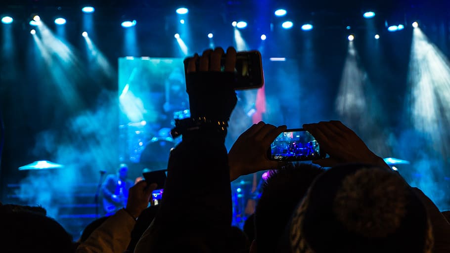 group of people holding smartphones watching concert, audience