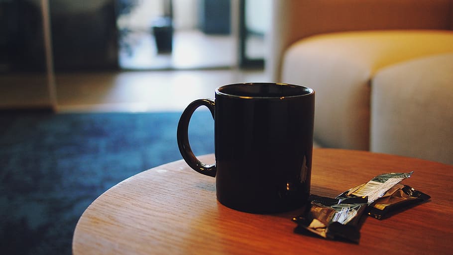 black ceramic mug placed on brown wooden coffee table selective focal photo