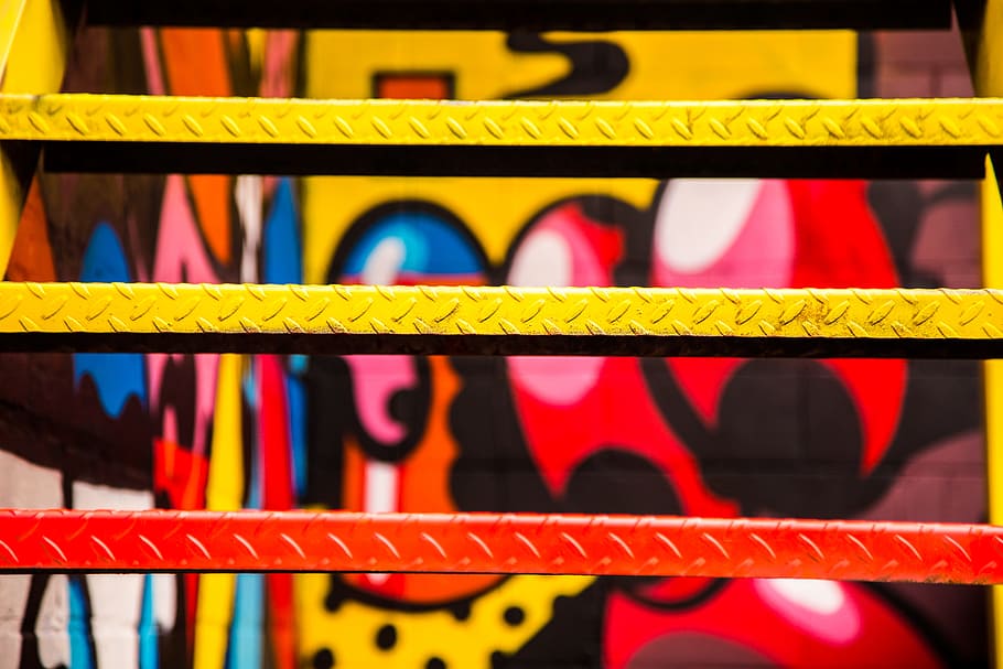 red and yellow painted metal stairs, closeup photo of red, yellow, and black wall graffiti HD wallpaper