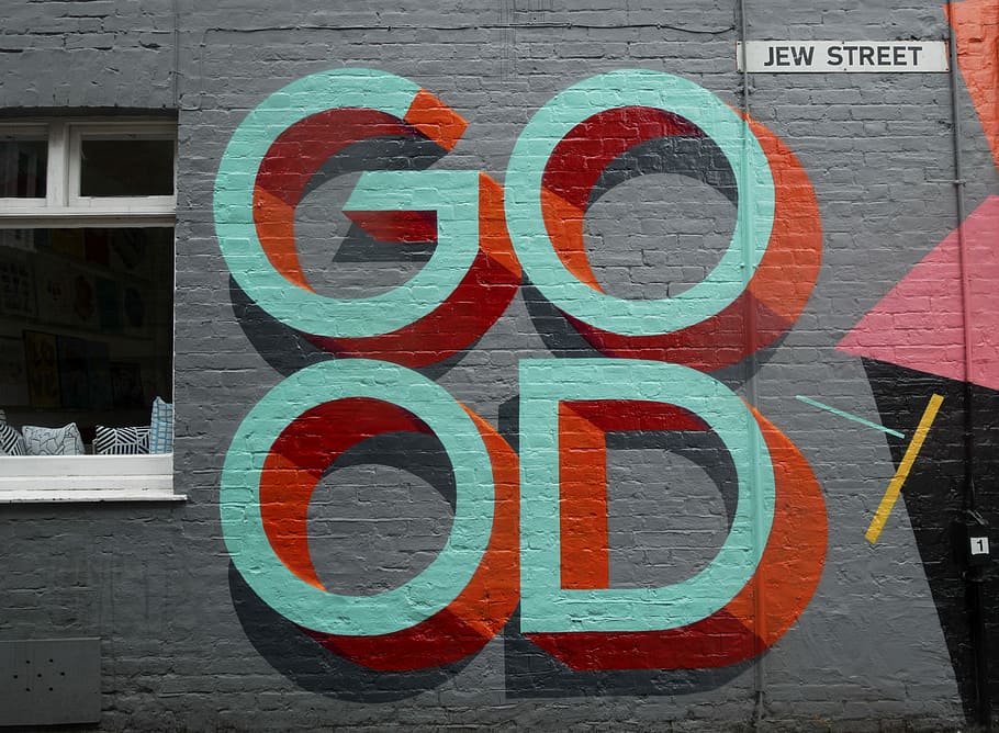Graffiti art sign on a gray brick wall on Jew Street that reads 