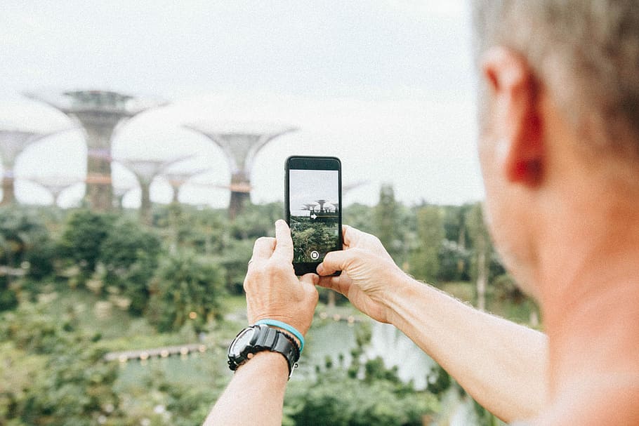 man taking picture using smartphone during daytime, person holding smartphone while taking picture of Supertree Grove, Singapore, HD wallpaper