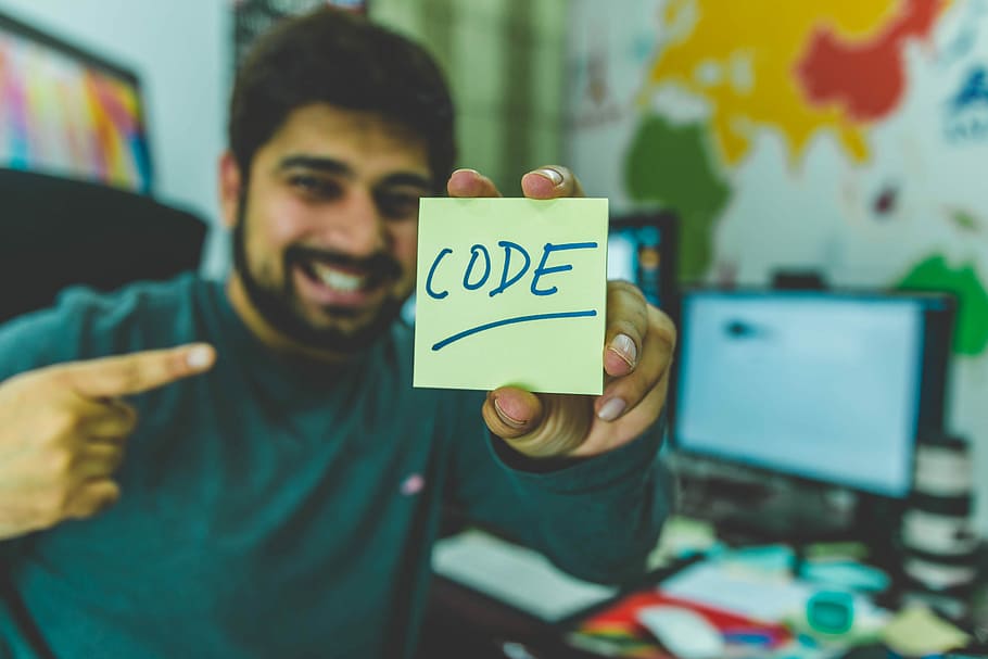 smiling man showing sticky note with code illustration, man holding sticky note with code text
