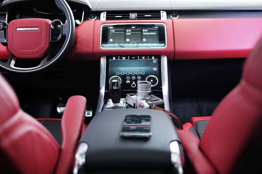 red and black vehicle interior, black smartphone on top of car center console
