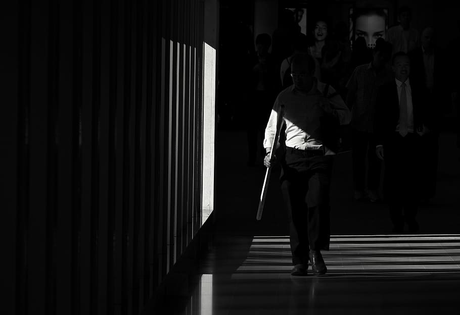 grayscale photography of man waking in the hall, low-light photo of man walking near wall HD wallpaper