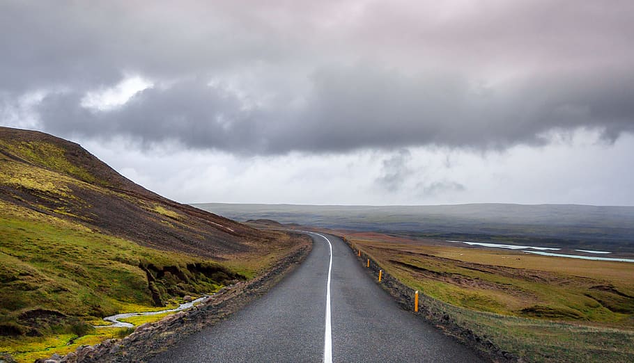 photography of road at daytime, empty gray concrete road top surrounded with green grass near shore during daytime HD wallpaper
