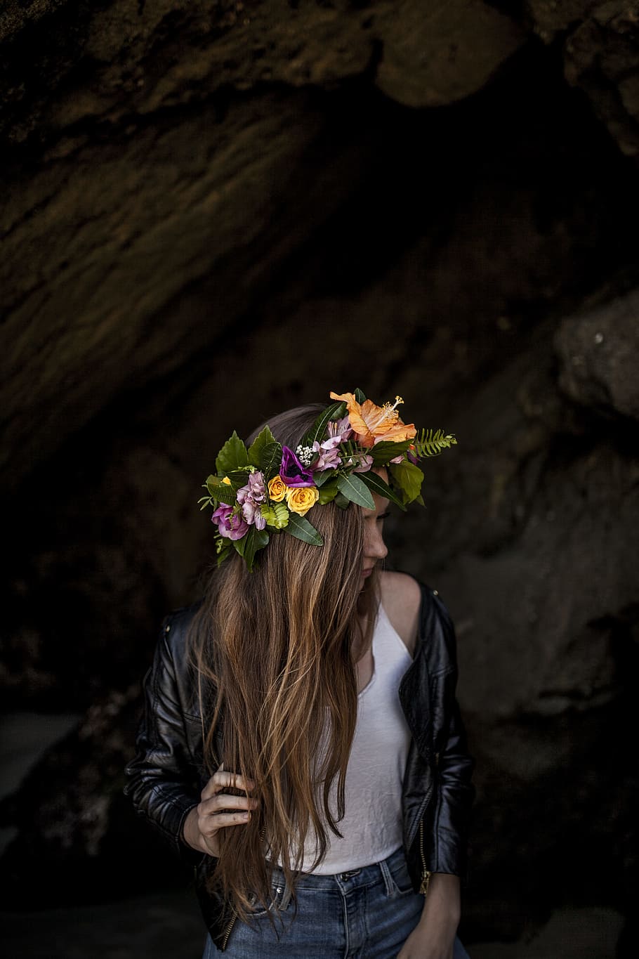 woman standing on dark area, woman in black leather biker jacket with yellow hibiscus flower headdress standing near grey making post during daytime HD wallpaper