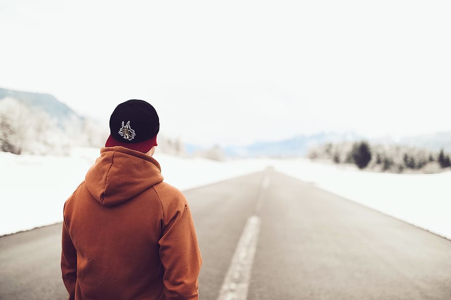 Person in Brown Hoodie Standing on Asphalt Road, blurred background HD wallpaper